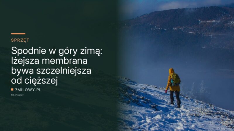Turysta w ciemnych spodniach i żółtej kurtce idzie ośnieżonym grzbietem górskim